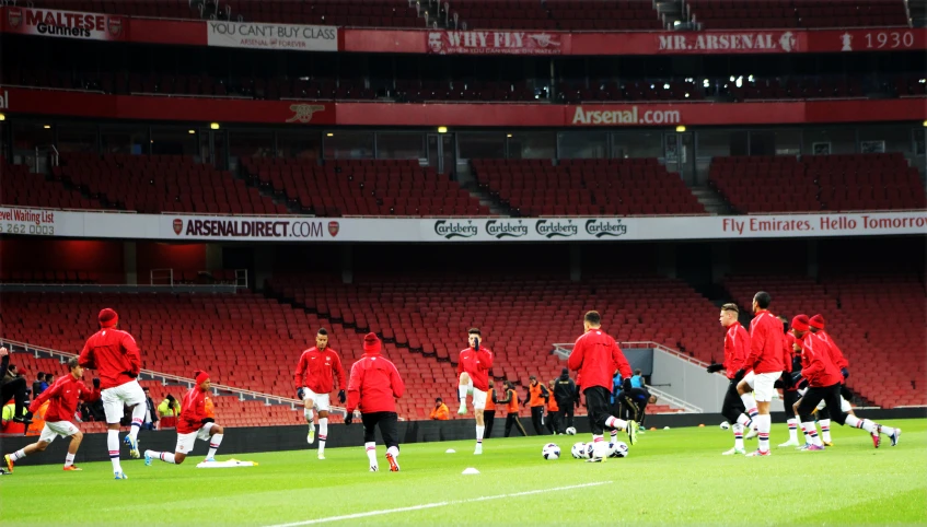 a group of men in red soccer uniforms walk on a field