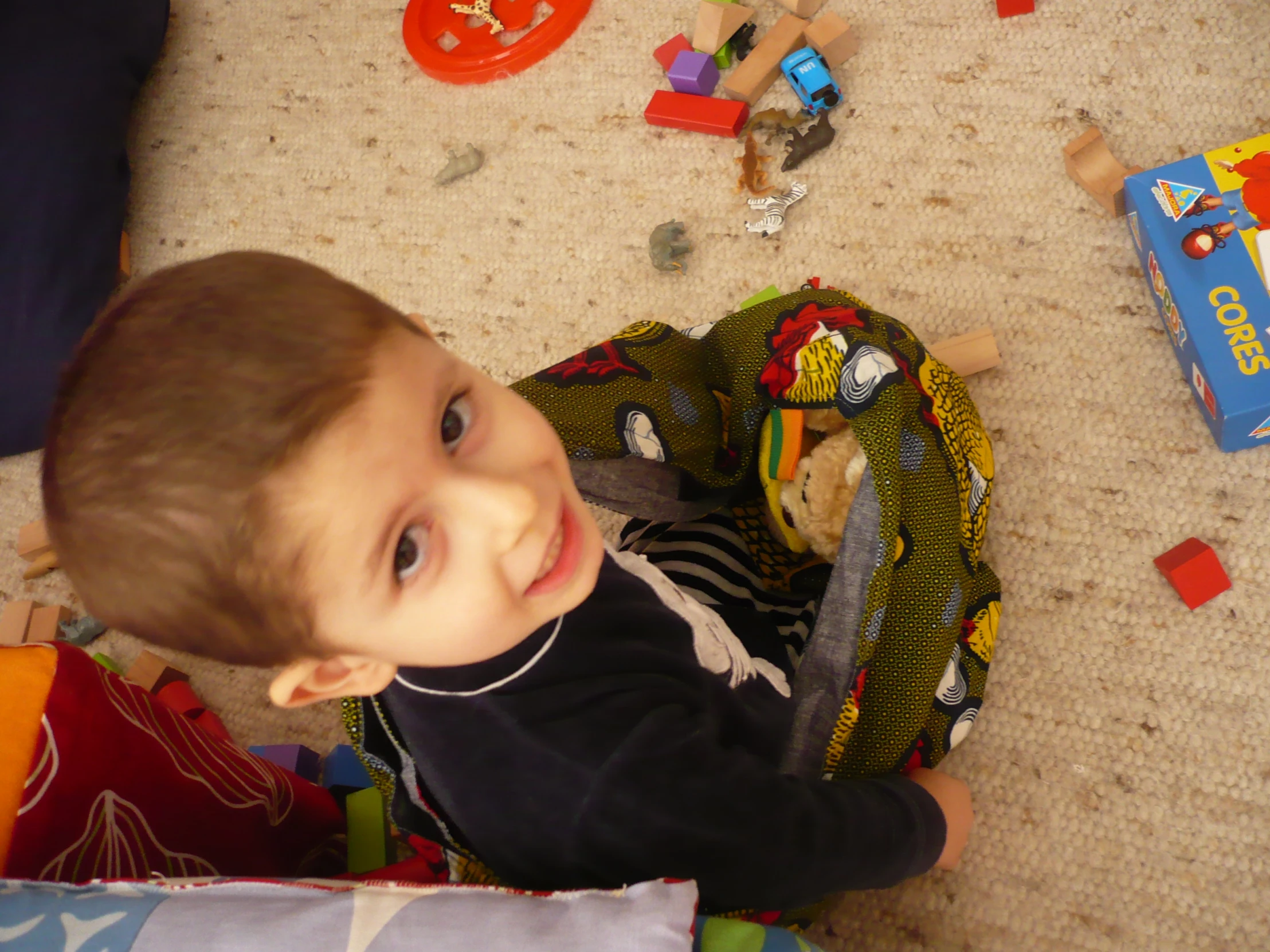 a small boy sitting on the floor with a bag