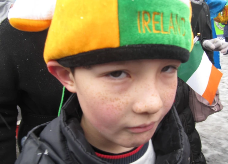 a small child wearing an irish hat while onlookers