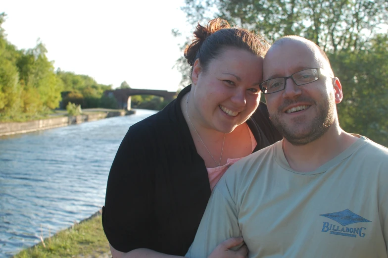 a man and a woman are posing by a river