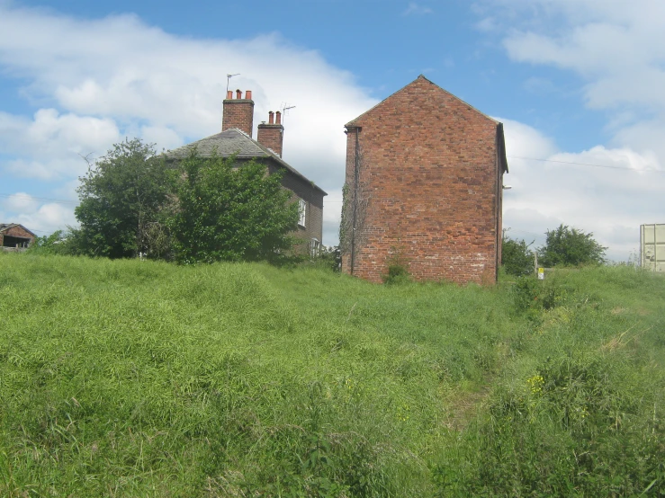 a red brick building on top of a grass covered hill