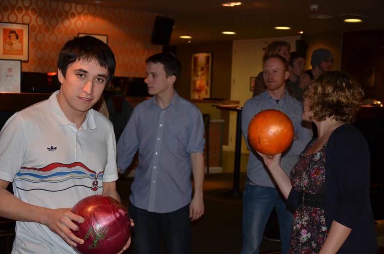 a man holding two bowling balls in one hand and a bowling ball in the other