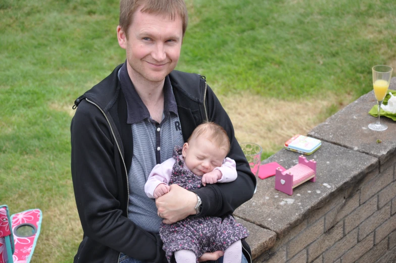 the man is holding his baby outside on the ledge