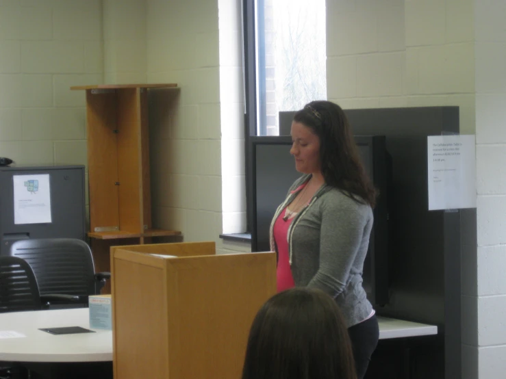 a woman standing next to a podium in a classroom