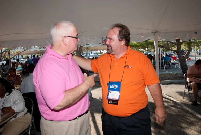 an older man standing next to another man