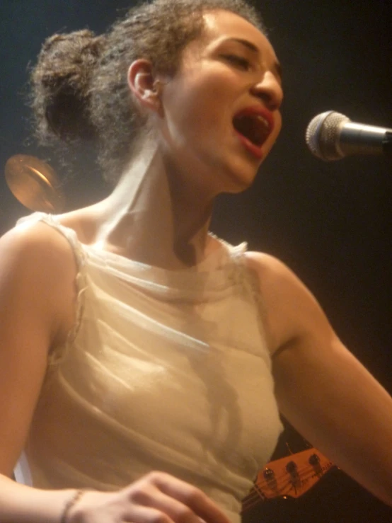 a woman singing into a microphone while holding a guitar
