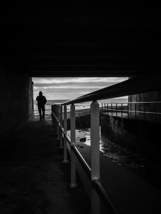 a silhouette of a person standing under an overpass