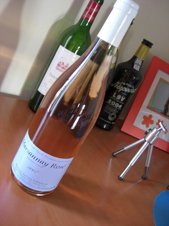 a wooden table topped with a wine bottle next to bottles