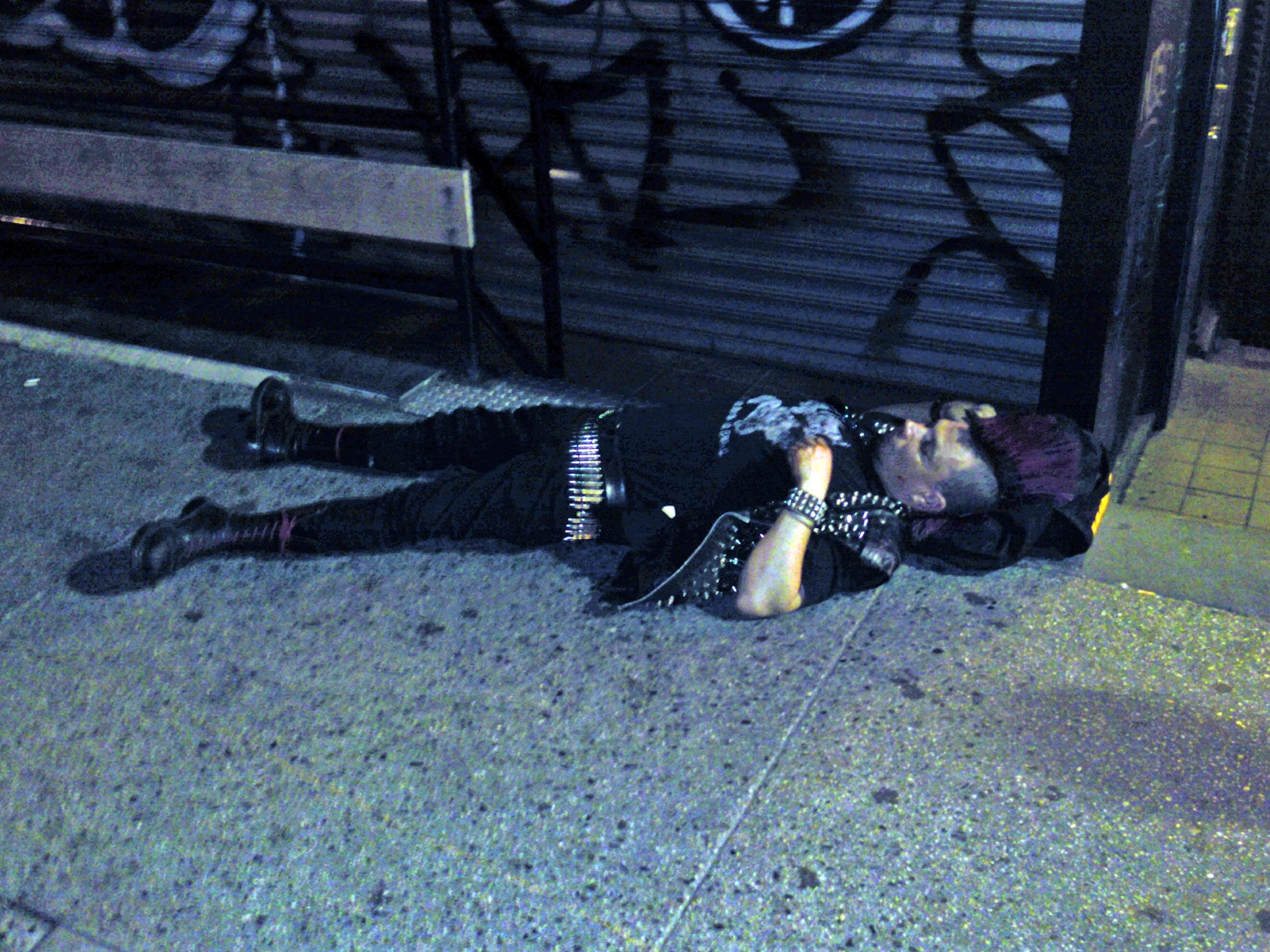 a young person lays on the ground next to a street