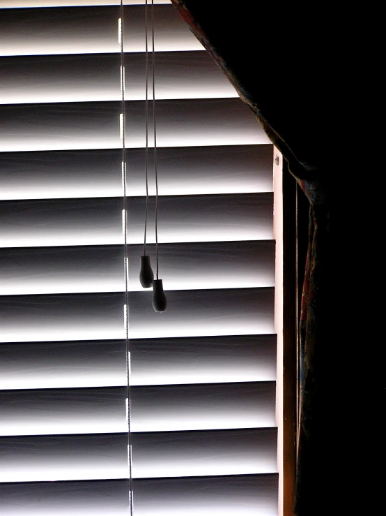 a window covered with white blinds and cords