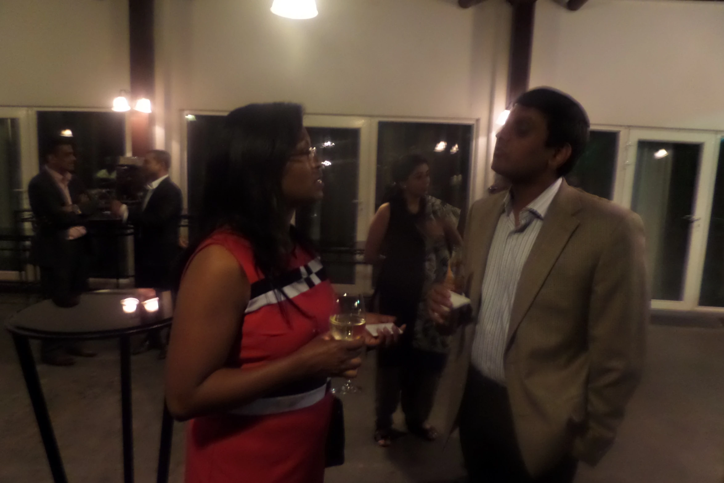 two woman wearing red and grey talking in a room with white walls