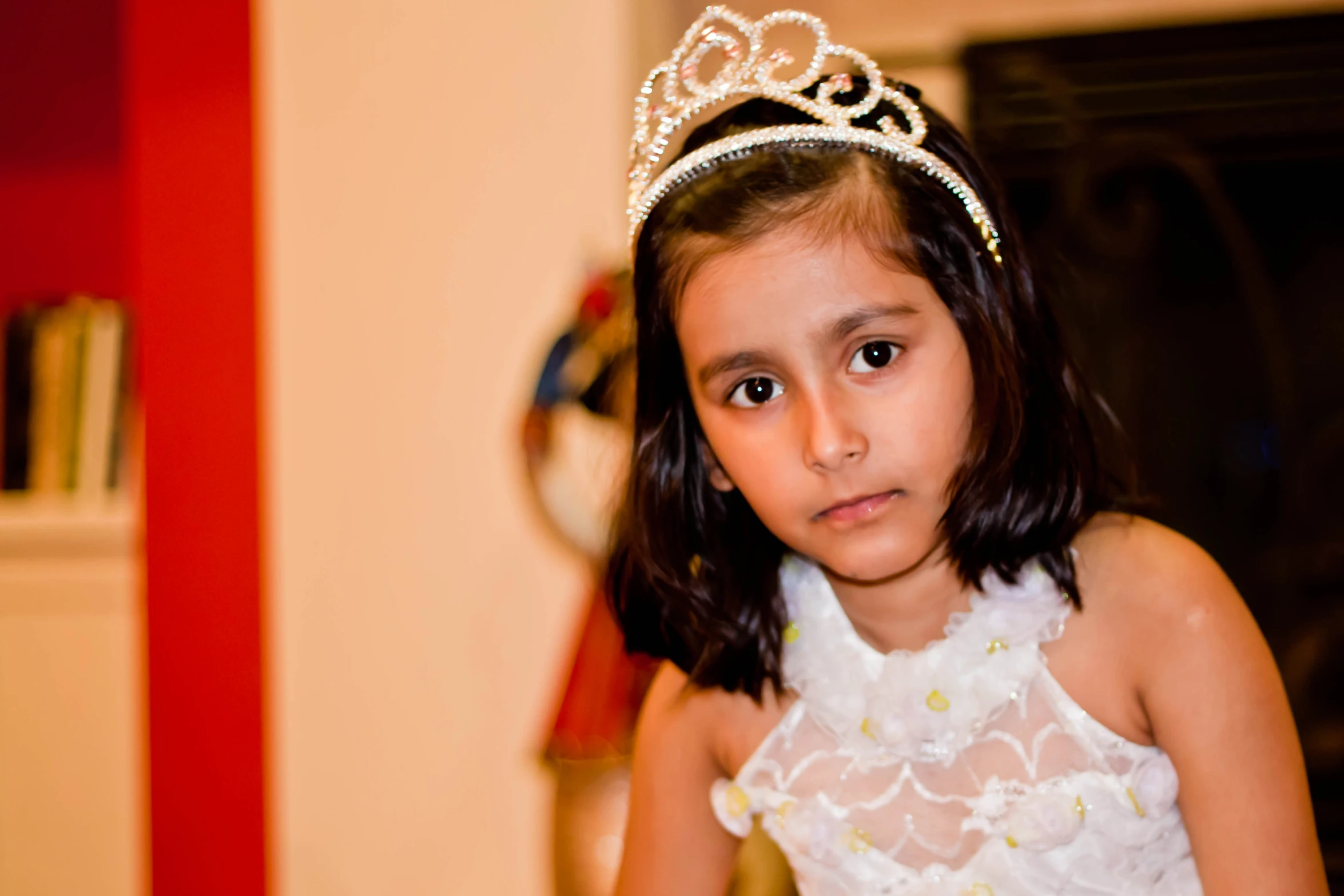 a girl with a tiara and dress looking off to the side