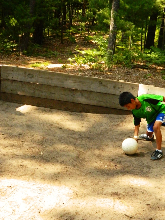 a little boy playing with a ball in the sand