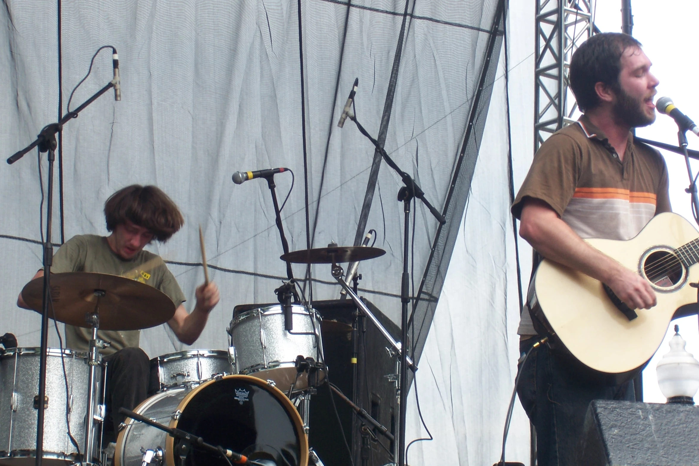 two men stand next to each other while playing guitars