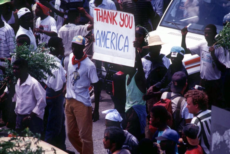 people marching in front of a bus with an american sign on the street