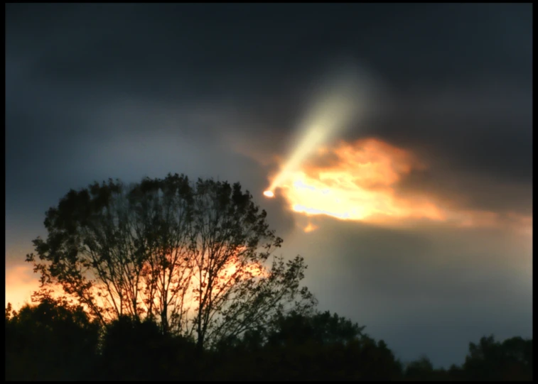 light shines through the clouds above trees