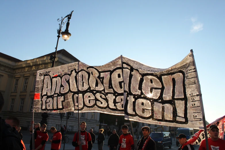 people stand on the street in front of an advertising banner