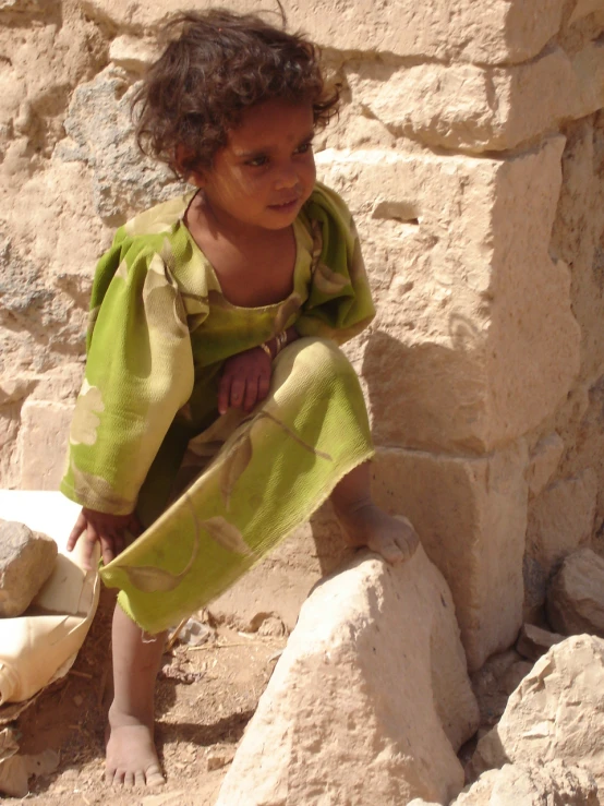 a girl sitting on a rock holding a towel