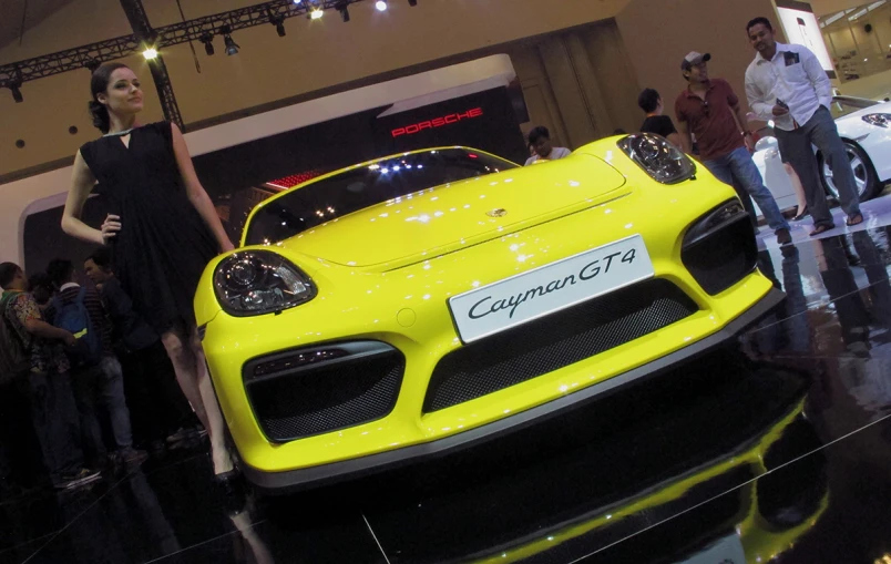 a young woman stands next to a large yellow car