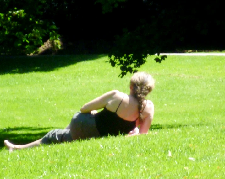 the woman is laying on the green grass