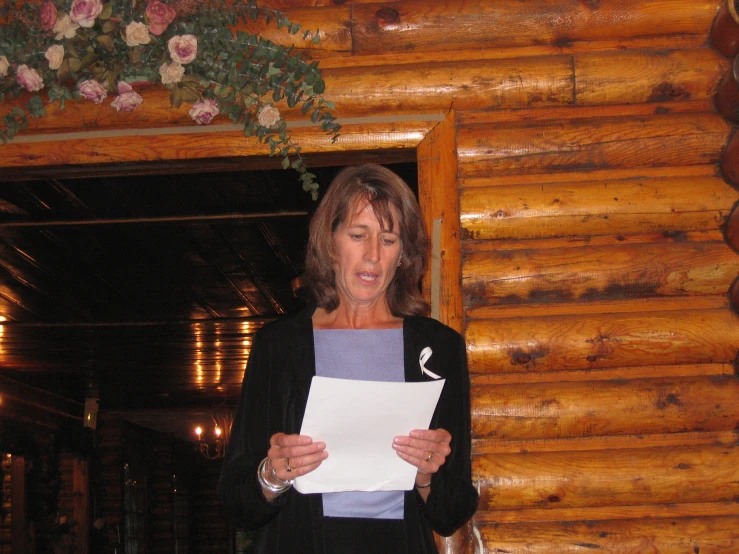 a woman wearing a black jacket and gray shirt holding a piece of paper