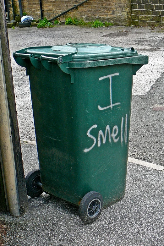 a trash can sitting on wheels with graffiti writing on it