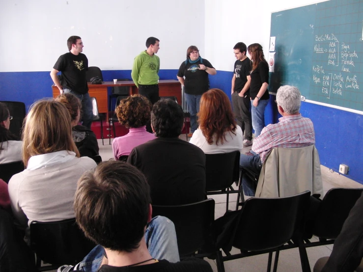 a group of people standing around in front of a class