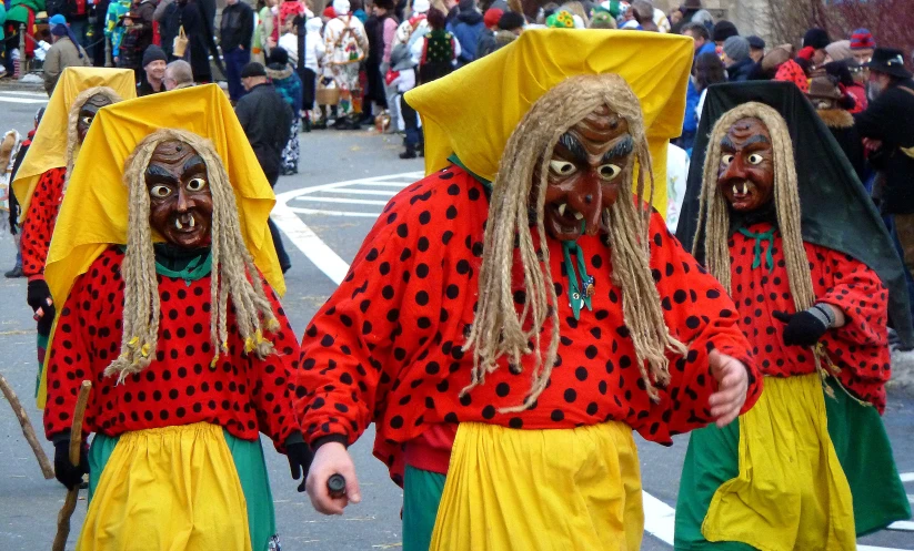 a group of people with various facial mask costumes walking on a street