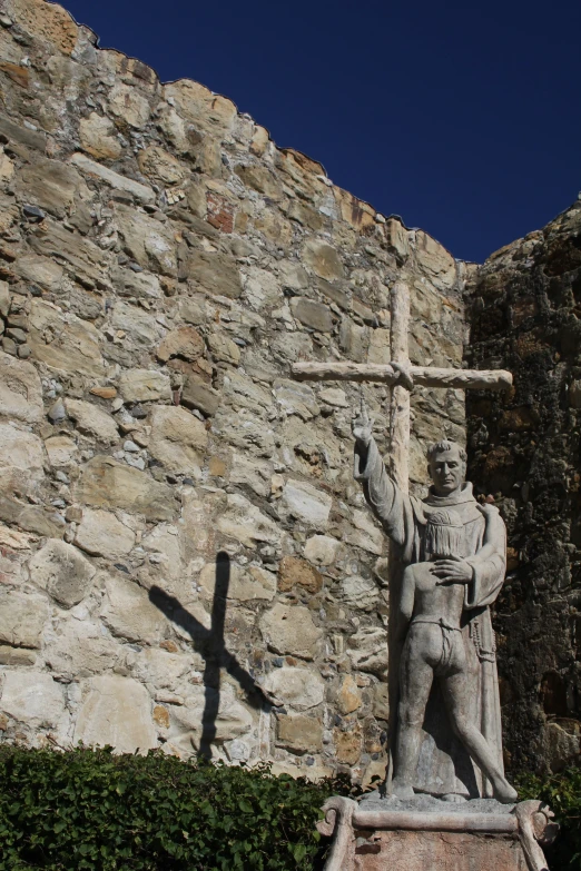 an old statue with a cross in front of a wall