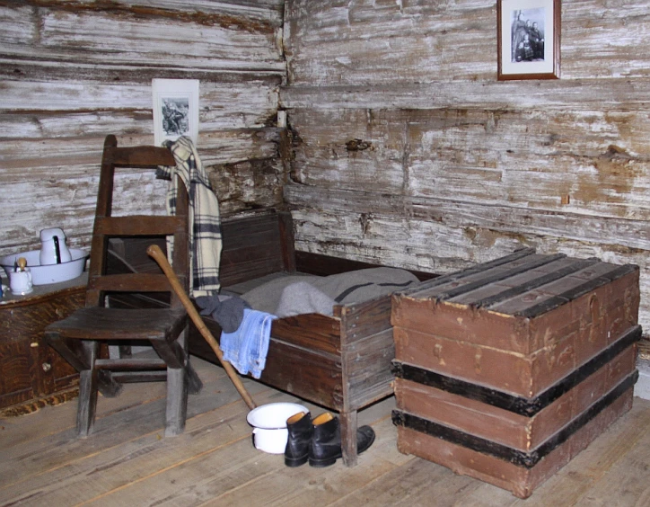 the room has a small bed with four trunks on the floor