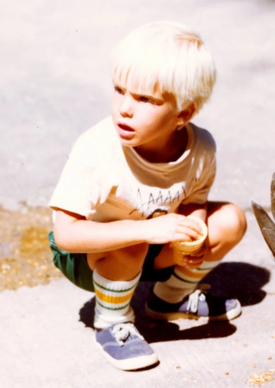 a boy that is sitting down with his hand on his knees