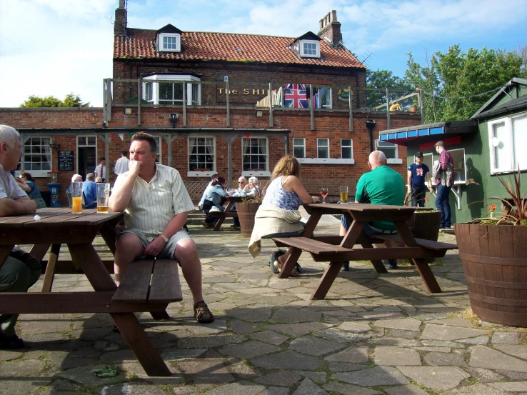 people are sitting at picnic tables in front of a building