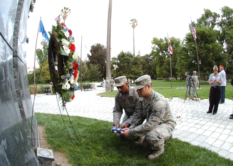 two uniformed military personnel placing flowers on a grave