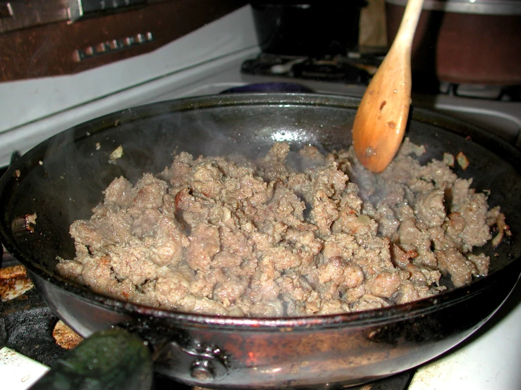 a wok pan with some meat cooking on top of it