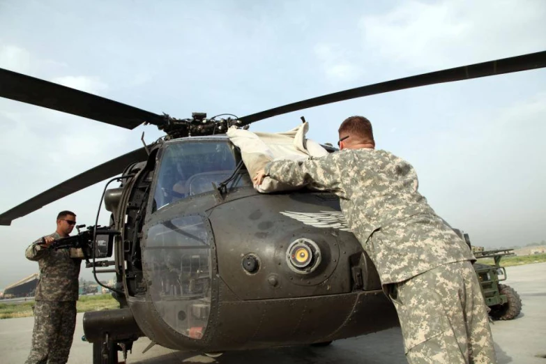 some soldiers are hanging out to get ready to board a helicopter