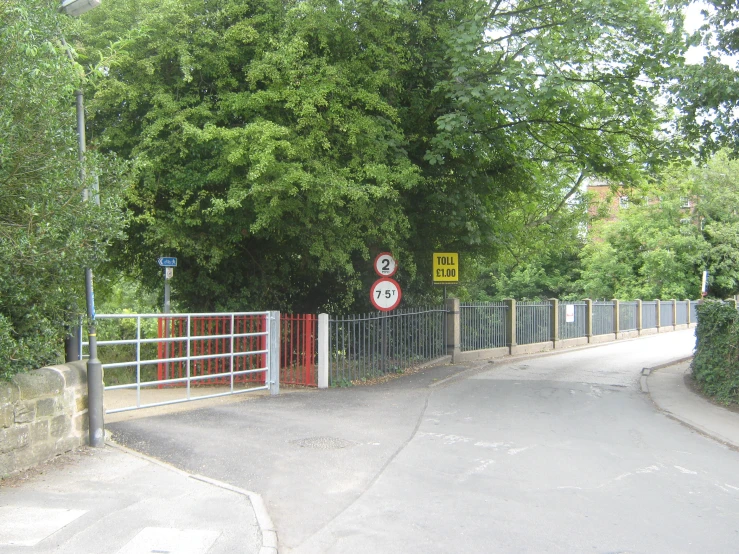 a road with gates, trees and signs