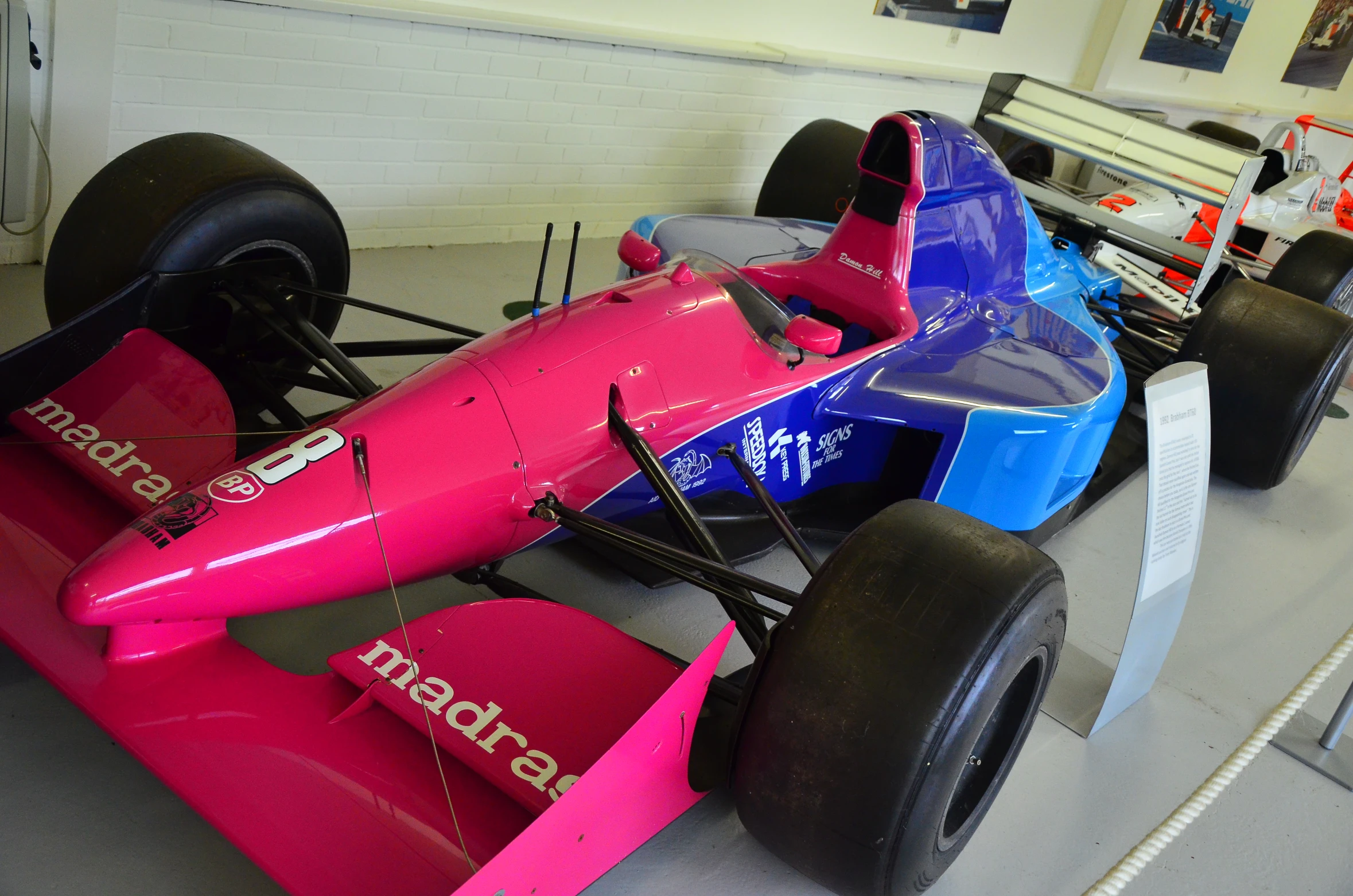 two large racing cars parked in an indoor garage