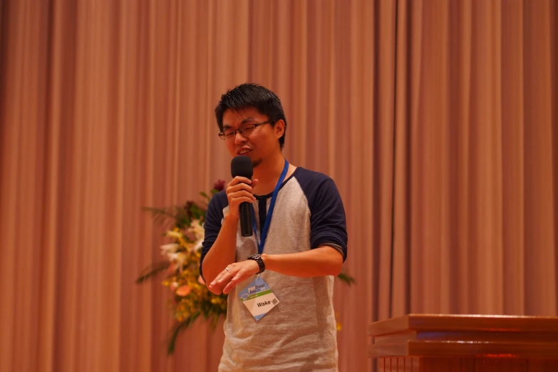 a man holding a microphone while standing next to a podium