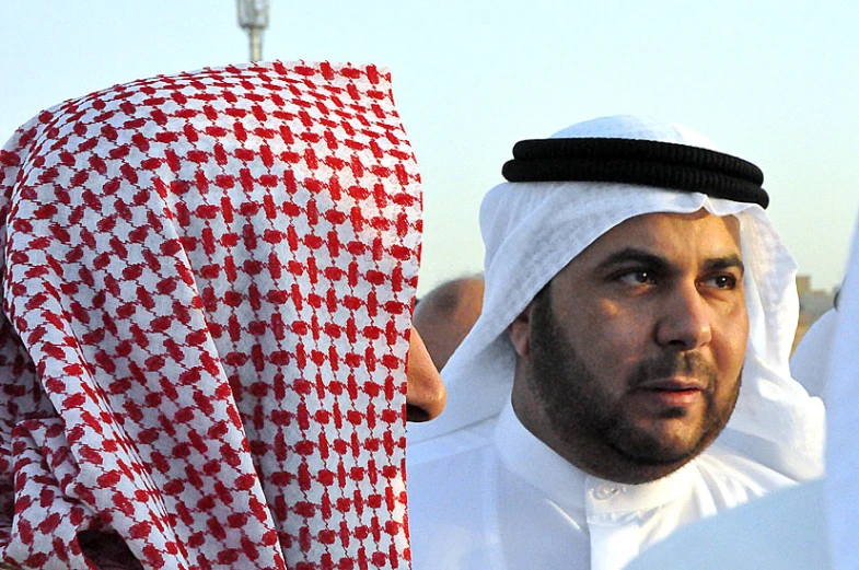 a man in a white turban holding his arm folded in a red and white checkerboard cloth