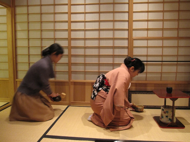 two women in oriental attire sitting on the floor playing with a board