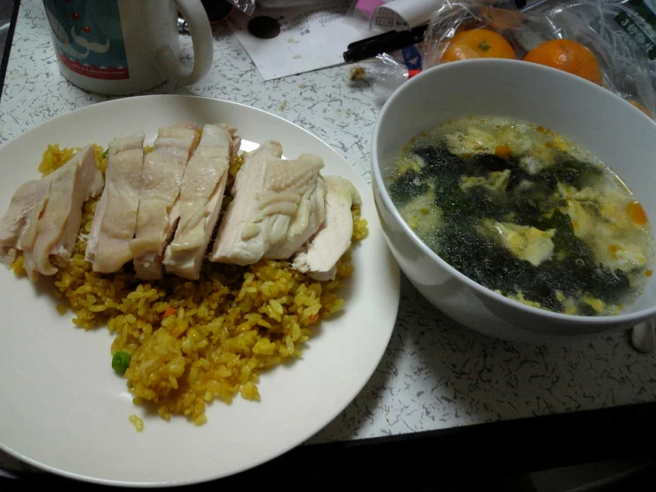 a white bowl filled with some meat next to a plate of rice