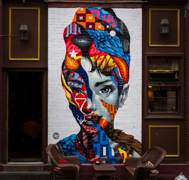 a picture on a brick wall of a man's face in colorful headdress