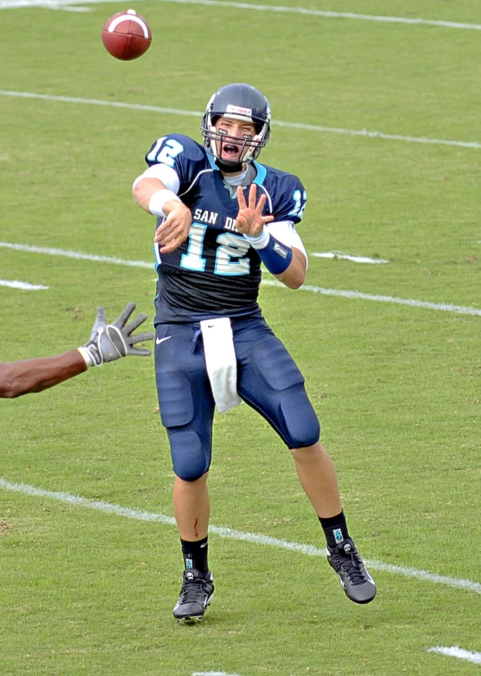 a man is throwing a football while another player jumps up to catch the ball