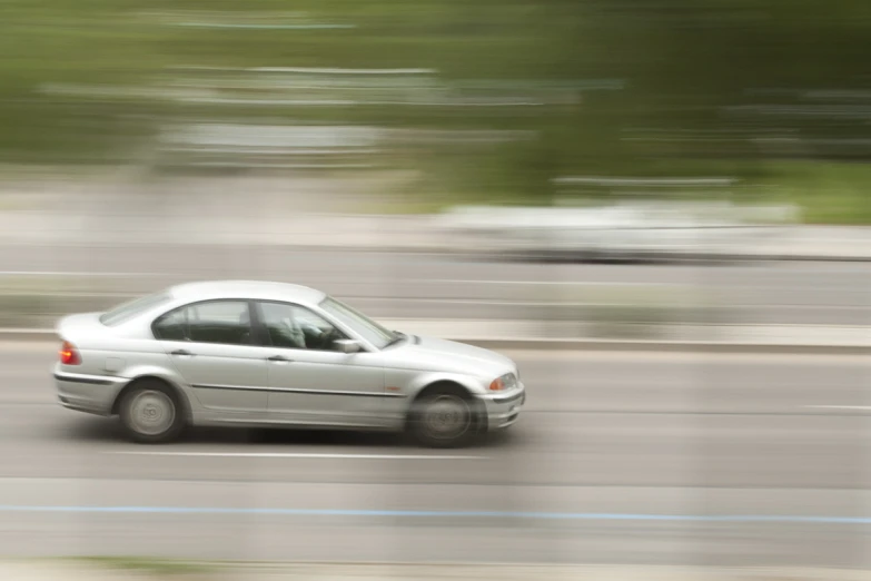 a silver car driving down a road on a blurry day