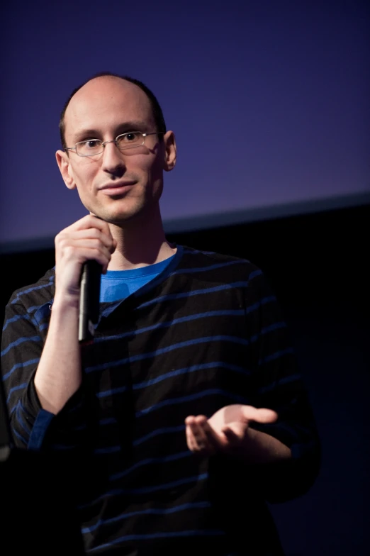 a man standing in front of a screen holding a microphone