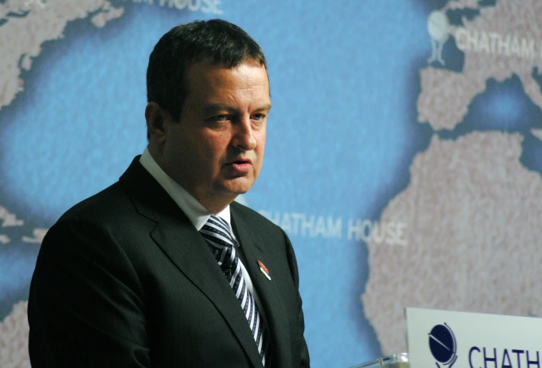 a man in a suit and tie standing next to a wall