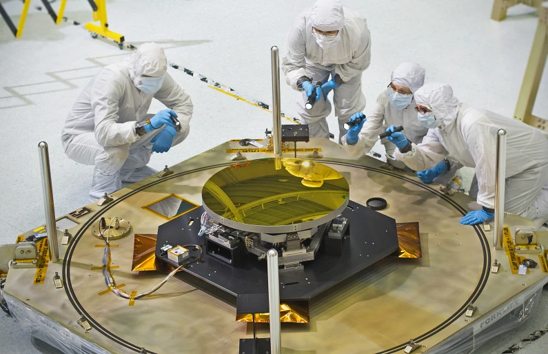 three people in white outfits are working on a big antenna