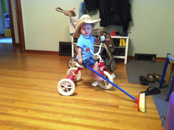 a toddler girl in a cowboy hat riding a tricycle