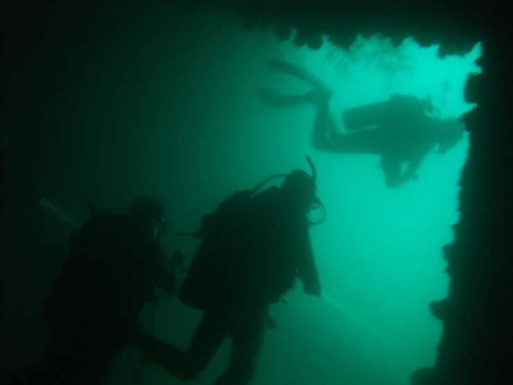 three scubamen are diving out of a boat