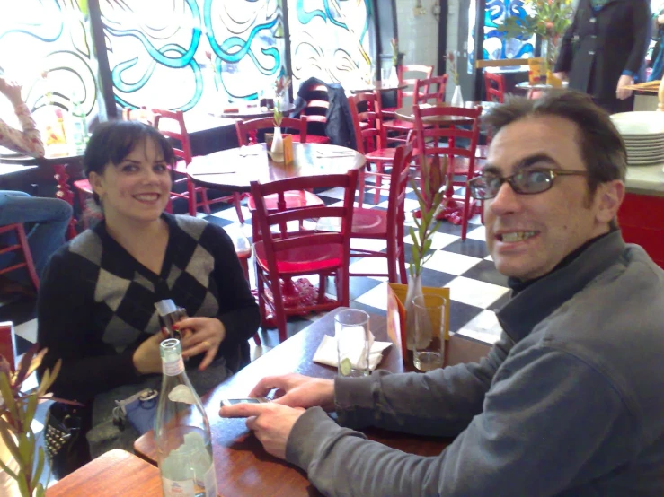 two people sit at a table together smiling for the camera